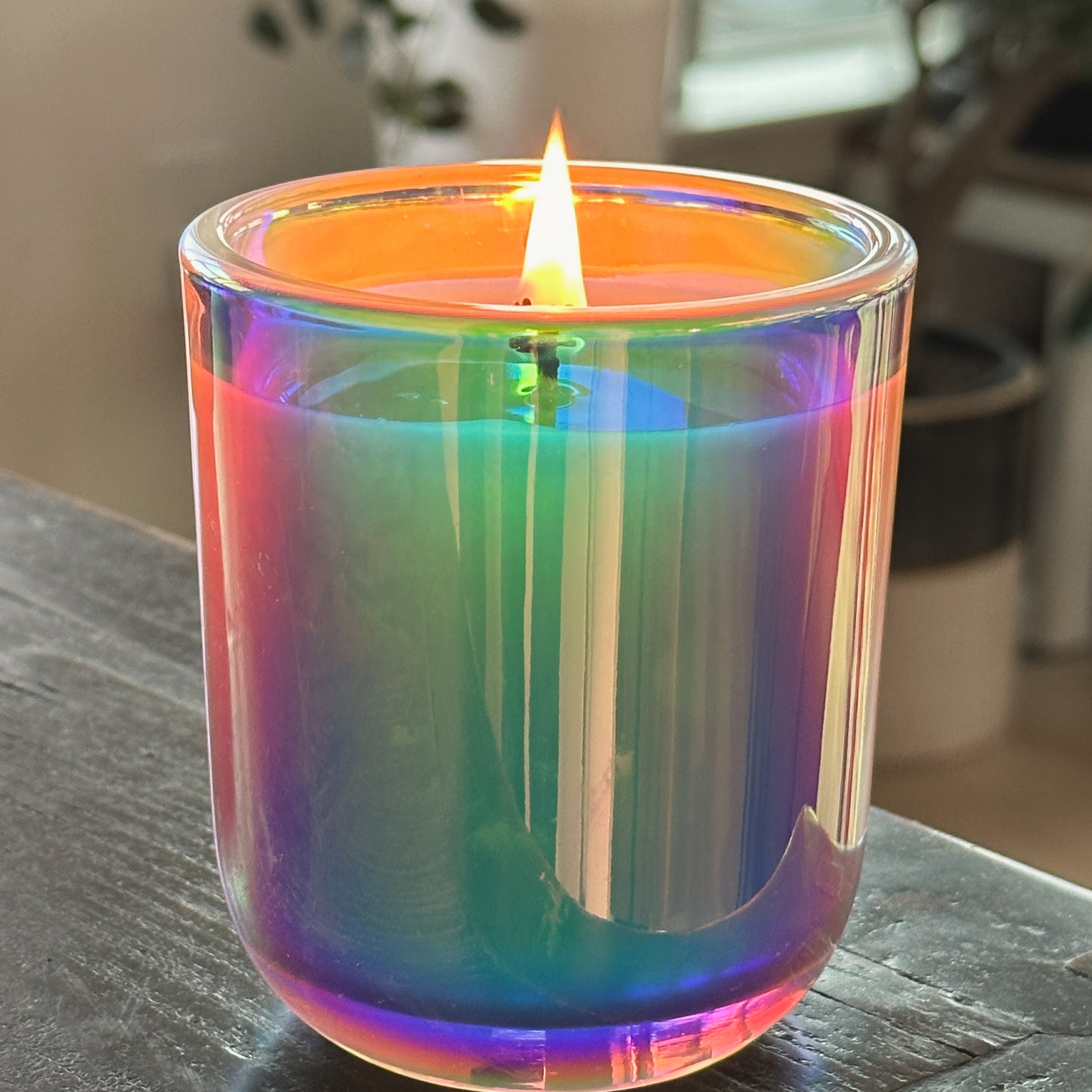 Colorful glass candle on a wooden surface with a blurred indoor background